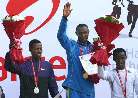 Geoffrey Mutai (R) of Kenya waves after winning gold in the men's  event of Delhi half Marathon, along with silver medallist Lelisa Desisa (L) of Ethiopia and bronze medal winner Yacob Yarso of Ethopia during the victory ceremony , in New Delhi