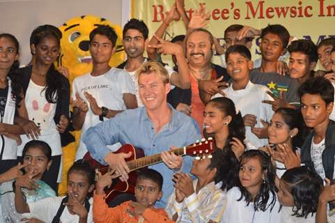 Brett Lee poses with a guitar and with the kids at Mewsic India Foundation