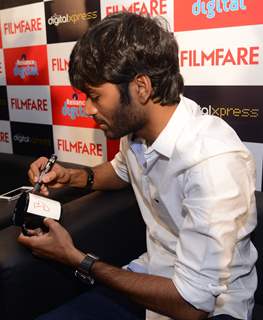 Dhanush signs a mug at the Filmfare Readers Meet at the Reliance Digital Store