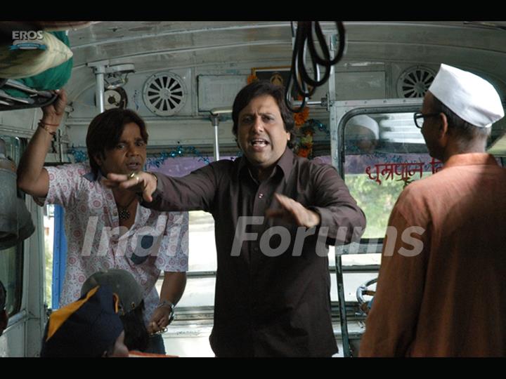 Govinda and Rajpal Yadav standing on a bus