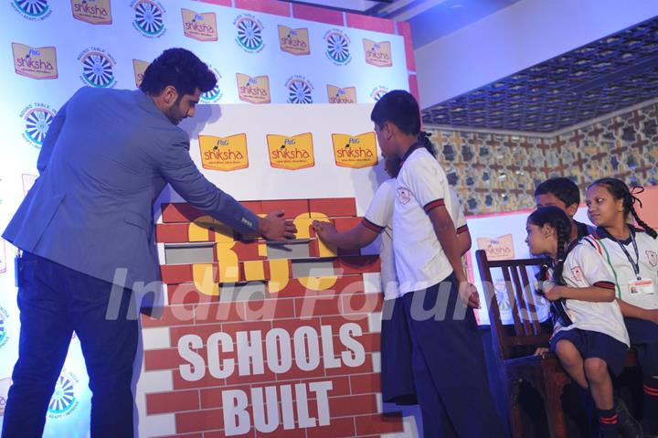 Arjun Kapoor helps the children solve a puzzle at a P&G Shiksha event