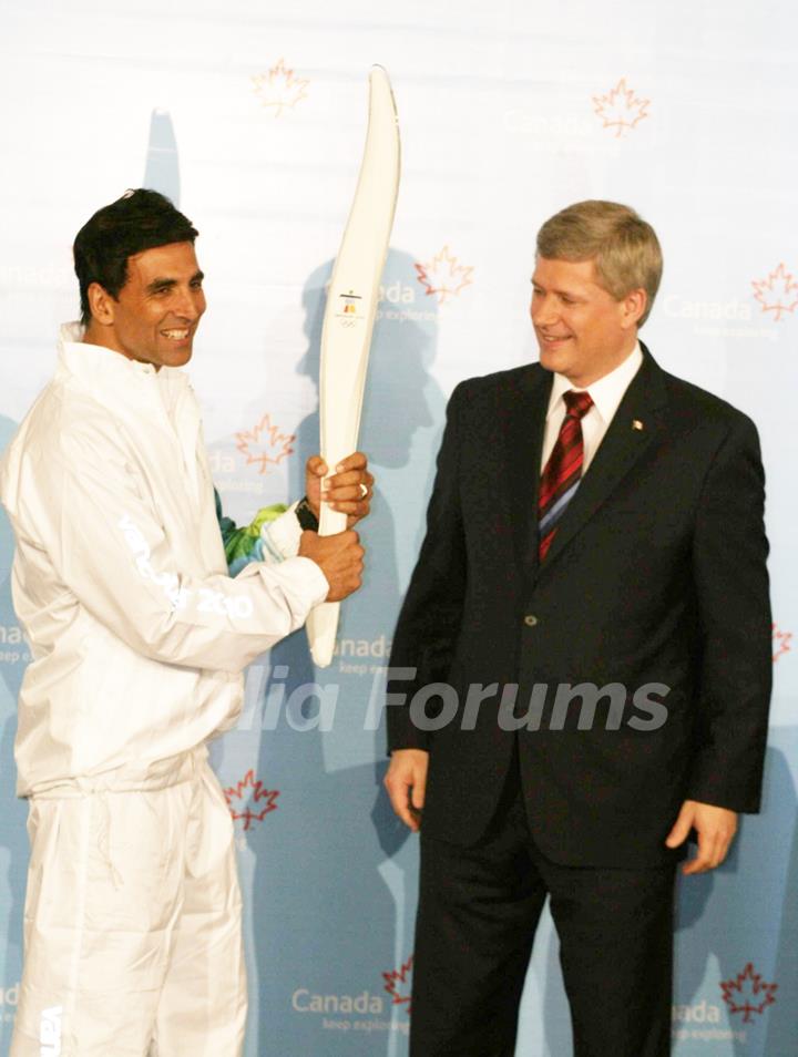 Canadian Prime Minister Stephen Harper and Bollywood Actor Akshay Kumar pose with a jacket, which will be worn by torchbearers for the 2010 Winter Olympics torch relay during an event at Trident in Mumbai on Monday, 16 November 2009