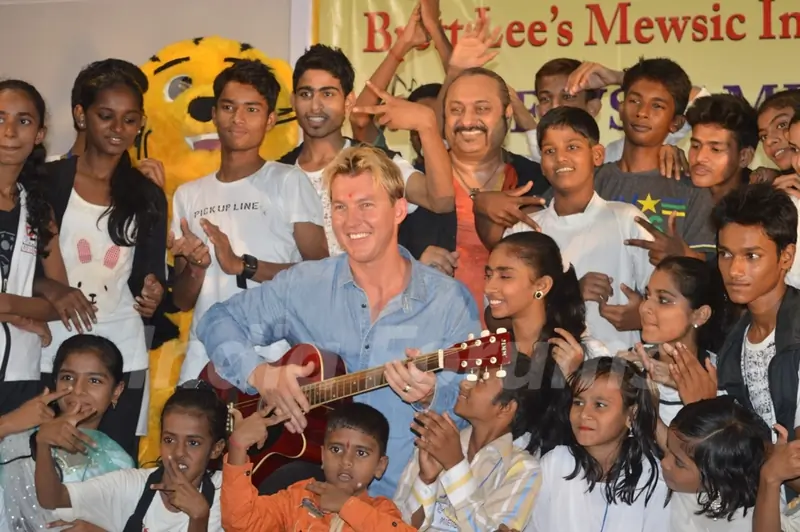 Brett Lee poses with a guitar and with the kids at Mewsic India Foundation